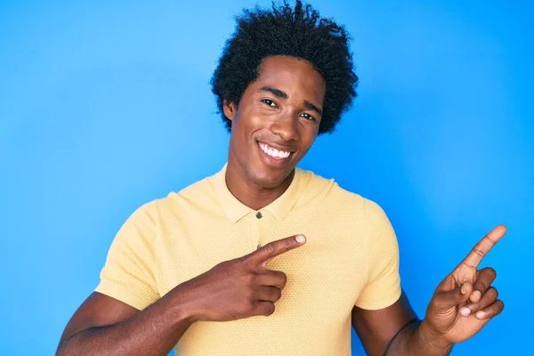 一个英俊的非洲裔美国男人 留着黑头发 穿着休闲装 面带微笑 看着摄像机 用双手和手指指向旁边 — 图库照片