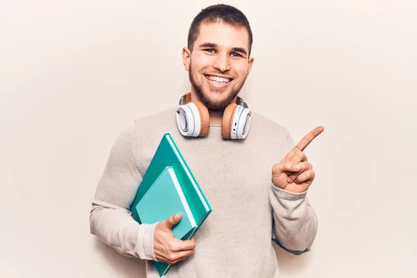 Junger Gutaussehender Mann Hält Buch Mit Kopfhörern Und Lächelt Glücklich — Stockfoto