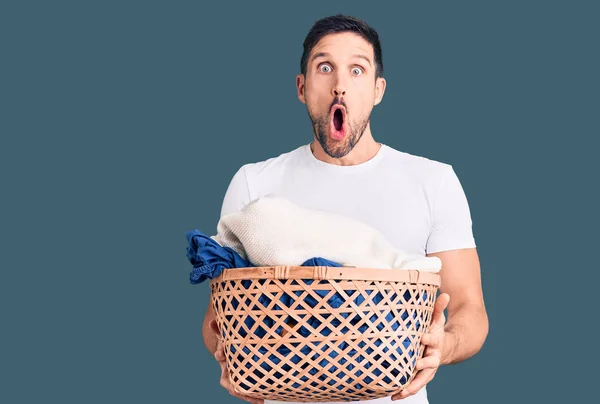 Young Handsome Man Holding Laundry Basket Scared Amazed Open Mouth — Stock Photo, Image