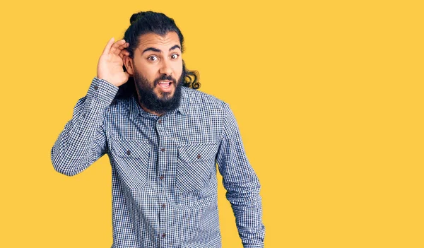 噂やゴシップに耳を傾ける耳の上に手で笑みを浮かべてカジュアルな服を着て若いアラブ人男性 聴覚障害の概念 — ストック写真