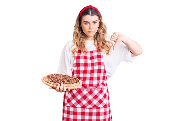 Νεαρή Λευκή Γυναίκα Που Φοράει Ποδιά Κρατώντας Πίτσα Θυμωμένο Πρόσωπο — Φωτογραφία Αρχείου