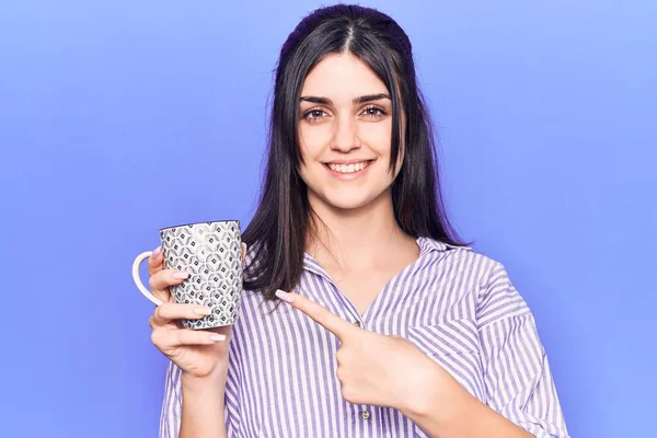 Junges Schönes Mädchen Trinkt Tasse Kaffee Lächelnd Glücklich Zeigt Mit — Stockfoto