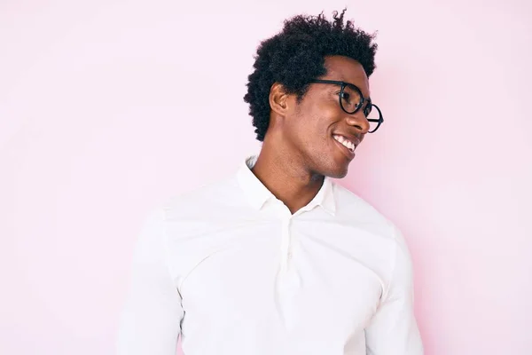 Handsome african american man with afro hair wearing business shirt and glasses looking to side, relax profile pose with natural face and confident smile.