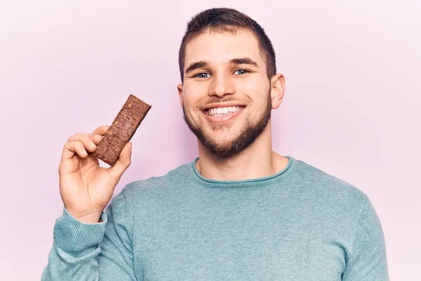 Homem Bonito Jovem Segurando Barra Proteína Olhando Positivo Feliz Sorrindo — Fotografia de Stock