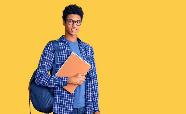 若いアフリカ系アメリカ人の男性学生のバックパックを顔に幸せとクールな笑顔で本を保持を着て 運のいい人 — ストック写真