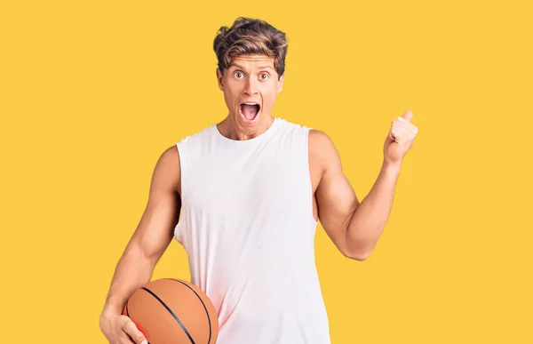 Joven Hombre Guapo Sosteniendo Pelota Baloncesto Gritando Orgulloso Celebrando Victoria — Foto de Stock