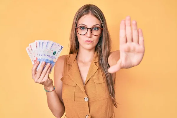 Jovem Loira Segurando Pesos Colombianos Com Mão Aberta Fazendo Sinal — Fotografia de Stock