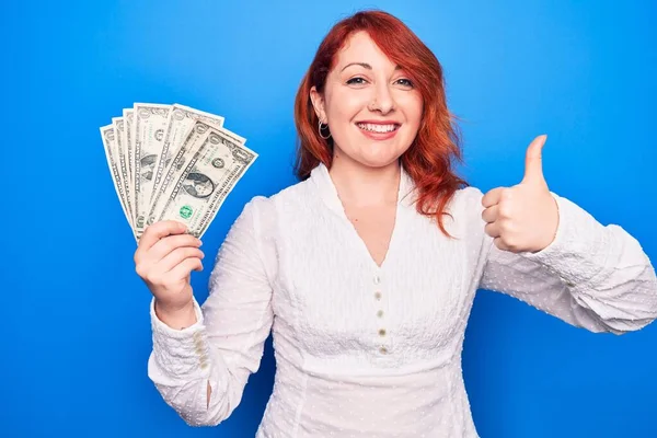 Junge Schöne Rothaarige Frau Hält Ein Bündel Dollarnoten Über Blauem — Stockfoto