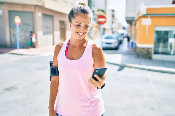 在城市里 中年女运动员用智能手机开心地微笑着 — 图库照片