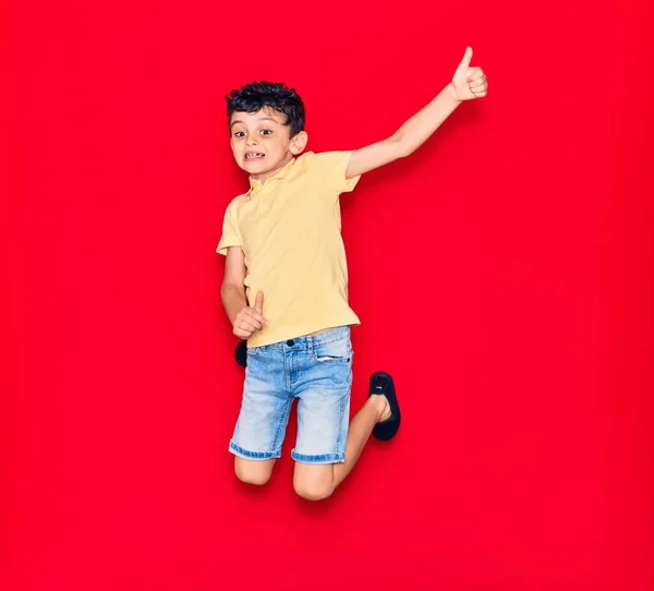 Adorable Niño Con Ropa Casual Saltando Sobre Fondo Rojo Aislado — Foto de Stock