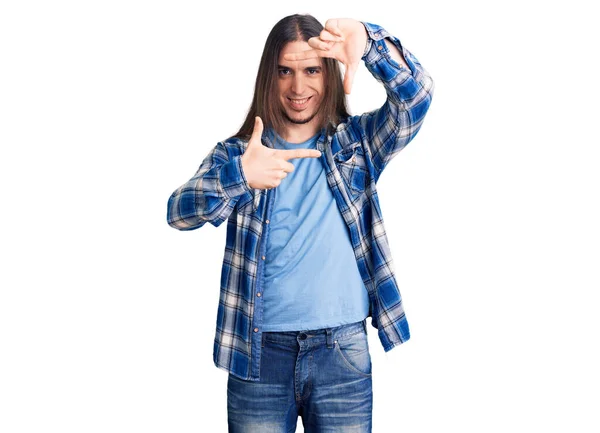 長い髪をしている若い大人の男性は 幸せな顔で手や指でフレームを作り笑顔カジュアルなシャツを着ています 創造性と写真の概念 — ストック写真