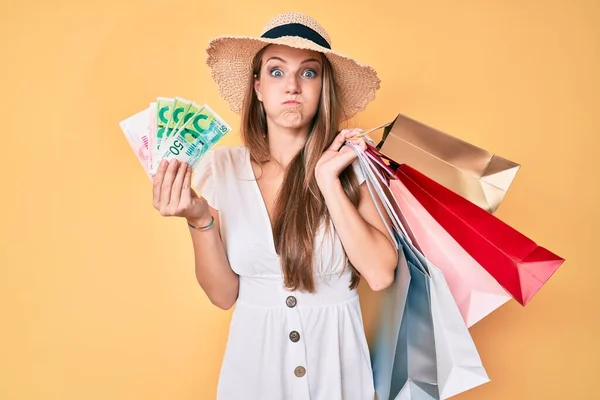 Young Blonde Girl Holding Shopping Bags Israeli Shekels Puffing Cheeks — Stock Photo, Image