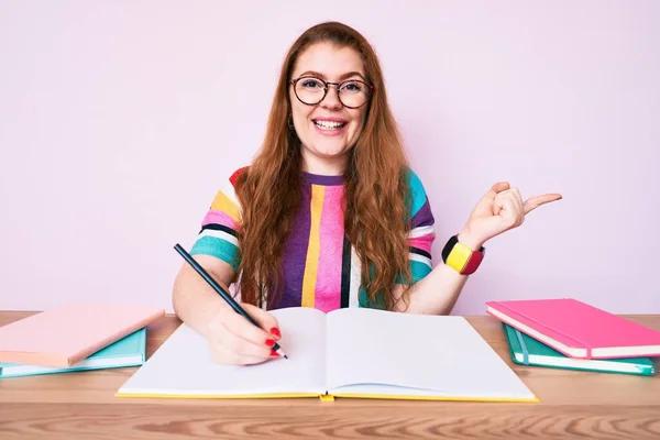 Jovem Ruiva Sentada Mesa Escrevendo Livro Sorrindo Feliz Apontando Com — Fotografia de Stock