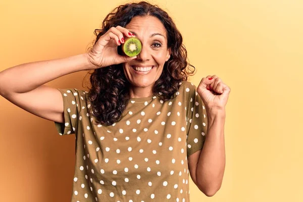 Mulher Bonita Meia Idade Segurando Kiwi Sobre Olhos Gritando Orgulhoso — Fotografia de Stock
