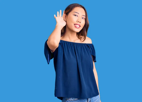 若い美しい中国の少女は 噂やゴシップに耳を傾け手で笑みを浮かべてカジュアルな服を着ている 聴覚障害の概念 — ストック写真