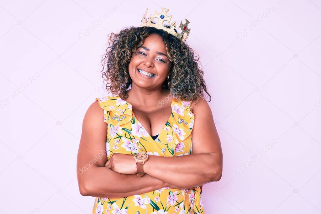 Young african american plus size woman wearing princess crown happy face smiling with crossed arms looking at the camera. positive person. 