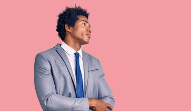 Afro saçlı, iş ceketi giyen, kollarını çapraz yapmış, ikna olmuş ve kendine güvenen yakışıklı Afro-Amerikan bir adam. 