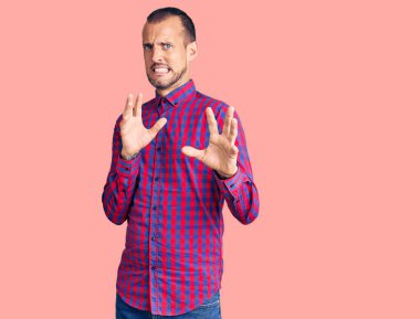 Gayri resmi giyinen genç yakışıklı adam tiksinti ifadesi takınıyordu. Tiksinti tepkisi yüzünden tiksinti ve korku ifadesi takınıyordu. Eller havada. 