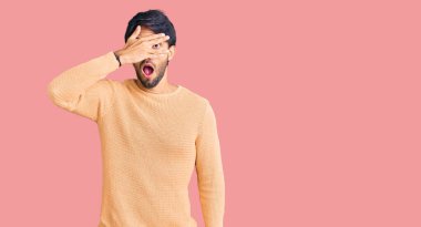 Yakışıklı İspanyol bir adam gündelik süveter giyiyor. Şoka giriyor, yüzünü ve gözlerini kapıyor. Utanmış bir ifadeyle parmaklarından bakıyor.. 