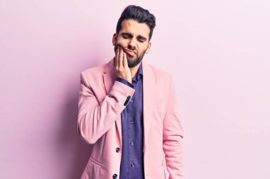 Sakallı, zarif bir ceket giyen, diş ağrısı ya da diş hastalığından dolayı ağızlarına acı dolu bir ifadeyle dokunan genç yakışıklı bir adam. dişçi 