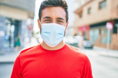 Kentin caddesinde duran yakışıklı İspanyol koruma maskesi takan yakışıklı adam..