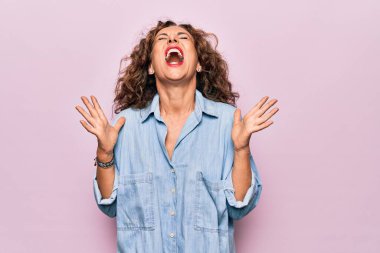 Orta yaşlı güzel bir kadın pembe arka planda dikilmiş kollarını kaldırmış ve gözleri kapalı heyecanla haykırarak başarıyı kutluyor. Kazanan konsept