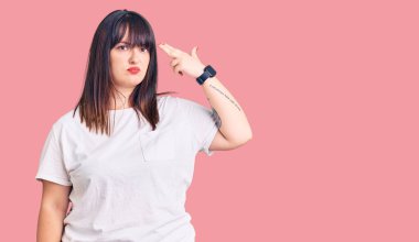 Genç ve cüsseli bir kadın gündelik giysiler giyip kendini vuruyor ve kendini vuruyor. Elini ve parmaklarını silah gibi kullanıyor. İntihar hareketi.. 