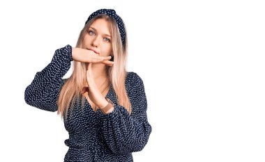 Genç, güzel, sarışın, gündelik giysiler giyen, el kol hareketleri yapan, hayal kırıklığına uğramış ve ciddi yüzlü bir kadın. 