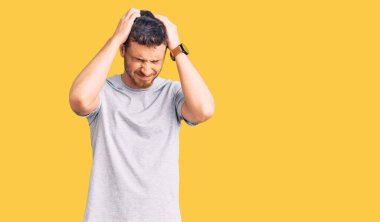 Ayılı yakışıklı genç adam, gündelik tişört giyiyor. Baş ağrısı çekiyor, çaresiz ve stresli. Çünkü acı ve migren ağrısı var. Eller başının üstünde.. 