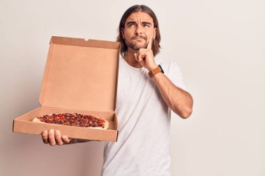 Elinde pizza kutusu olan yakışıklı bir adam ciddi bir yüz ifadesi olan eli çenesinde soru soran kafa karıştırıcı bir fikir hakkında düşünceli bir genç. 