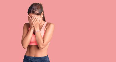 Ağlarken yüzünü ellerle kapatan, spor kıyafetleri giyen genç ve güzel bir İspanyol kadın. depresyon kavramı. 