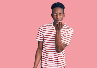 Gündelik giysiler giymiş genç Afro-Amerikan bir adam kameraya bakıp havada el ele öpüşerek sevimli ve seksi oluyor. aşk ifadesi. 