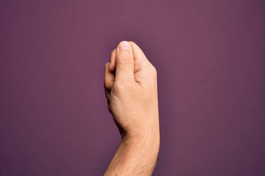 İzole edilmiş mor arka planda parmaklarını gösteren beyaz bir gencin eli parmak, iş ve reklamla boş bir alan tutuyor.