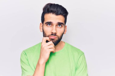 Sakallı, sıradan tişörtlü, yakışıklı, ciddi yüzlü, eli çenesinde soru soran, kafa karıştırıcı fikirleri düşünceli genç bir adam. 