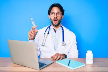 Klinikteki yakışıklı İspanyol doktor elinde şırıngayla şaşırmış ve şaşkın bir şekilde ağzı açık kaldı. 