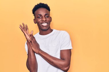 Genç Afro-Amerikan adam günlük giysiler içinde alkışlıyor ve mutlu ve neşeli alkışlıyor, gururla gülümsüyor. 