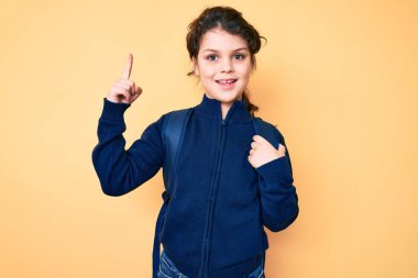 Sırt çantası tutan sevimli İspanyol çocuk bir fikre ya da soru işaretine şaşırdı ve mutlu bir yüzle işaret etti. 