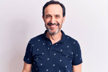 Yüzünde mutlu ve havalı bir gülümsemeyle izole edilmiş beyaz arka planda duran sıradan polo giyen orta yaşlı yakışıklı bir adam. Şanslı kişi..