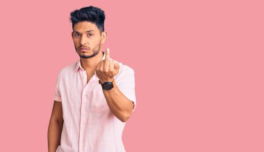 Handsome latin american young man wearing casual summer shirt showing middle finger, impolite and rude fuck off expression 