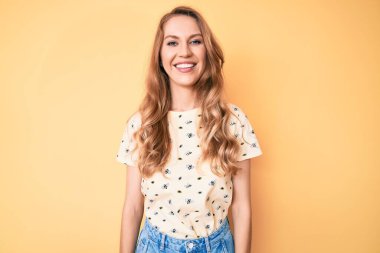 Sarı saçlı, günlük yaz kıyafetleri giyen mutlu ve havalı bir gülümsemesi olan beyaz bir kadın. şanslı kişi. 