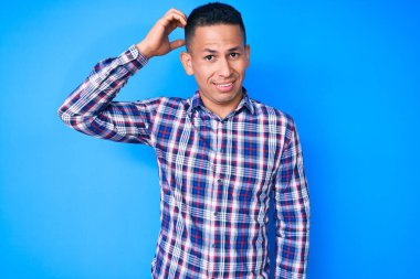 Gündelik giysiler giyen genç, yakışıklı latin adam soru sorup kafasını karıştırıyor. Şüpheyle kararsız, kafa kafaya düşünerek. Düşünceli kavram. 