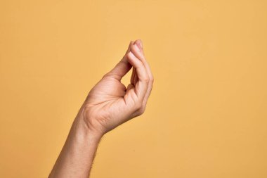 Kafkas genci parmaklarını izole edilmiş sarı arka planda gösteriyor. Parmaklarıyla İtalyan hareketi yapıyor. İletişim hareketi.