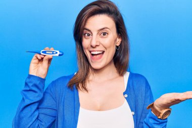 Termometreyi tutan genç ve güzel bir kadın başarıyı mutlu bir gülümsemeyle ve kazanan bir ifadeyle kutluyor. 