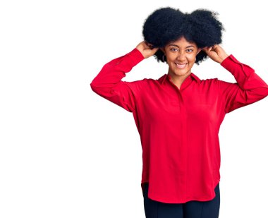 Genç Afro-Amerikalı kız günlük kıyafetler giyip gülümsüyor kulakları parmaklarıyla çekiyor, komik bir jest. deneme sorunu 