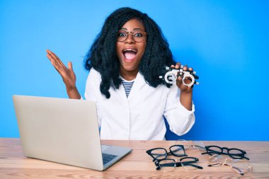 Güzel Afrikalı kadın elinde optometri gözlükleriyle zaferi mutlu bir gülümsemeyle kutluyor ve kazanan el kaldırarak ifade ediyor 