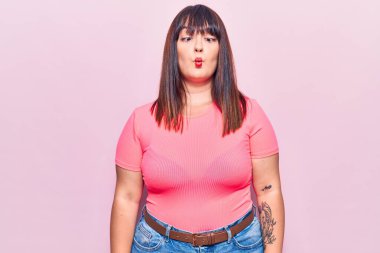 Genç ve cüsseli bir kadın günlük kıyafetler giyiyor, dudaklarıyla balık suratı yapıyor, çılgınca ve komik hareketler yapıyor. Komik ifade. 