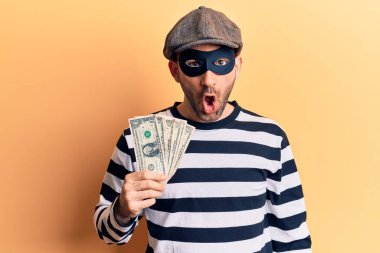 Hırsız maskesi takan genç ve kel bir adam dolar çalıyor. Banknotlar çalıyor. Şaşırmış ve şaşırmış bir şekilde ağzı açık. 