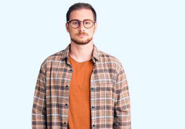 Yüzünde ciddi bir ifade olan günlük kıyafetler ve gözlük takan yakışıklı beyaz bir adam. Basit ve doğal bir şekilde kameraya bakıyorsun.. 