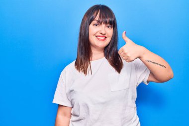 Genç ve cüsseli kadın güler yüzlü, mutlu ve pozitif, başparmak yukarı mükemmel ve onay işareti yapıyor. 