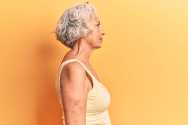 Kıdemli, gri saçlı, günlük kıyafetler giyen, rahat bir görünüm takınan, doğal yüzlü ve kendine güvenen bir gülümseme takınan bir kadın.. 